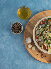 fresh vegetable salad with olive oil in a plate on a blue background.