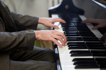 Close-up of male hands pushing on the keys of grand piano and playing the classical music at lesson
