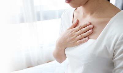 Young woman putting her hand on her chest. Having a pain in chest, Gastroesophageal Reflux Disease  have frequent belching. Healthcare medical concept.