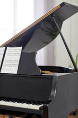 Image of vintage grand piano with sheet music on the stand for pianist standing in the room