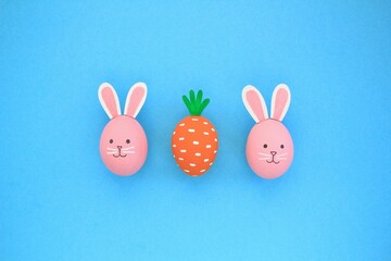 Easter eggs pattern made with painted carrot and bunnies on blue background. Creative minimal holiday concept. Funny idea for greeting card, poster, banner, advertising, web. Top view, flatlay