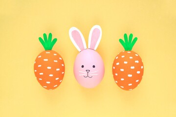 Easter eggs pattern made with painted carrots and bunny on yellow background. Creative minimal holiday concept. Funny idea for greeting card, poster, banner, advertising, web. Top view, flatlay