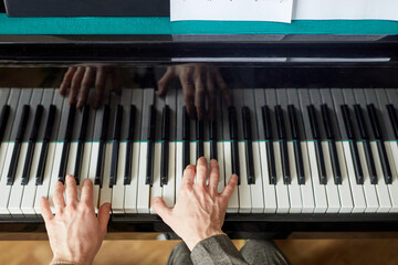 Close-up of male hands pushing on the black and white keys and playing the music on grand piano