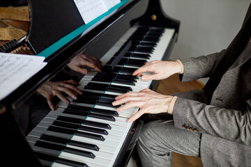 Close-up of pianist in suit playing the classical music on the piano at musical lesson