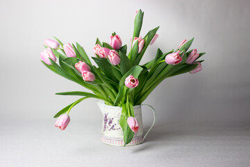 Fresh pink tulip flowers bouquet on shelf in front of stone wall. View with copy space