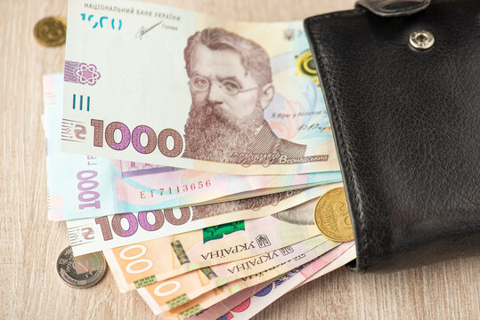 Photo of black leather purse with ukrainian hryvnia banknotes and coins
