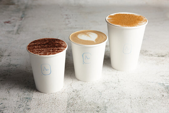 Three takeaway coffees lined up on bench
