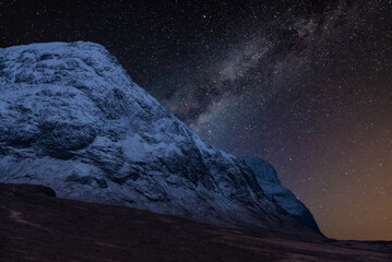 Majestic vibrant Milky Way composite image over landscape of snowcapped Winter mountains in Scotland