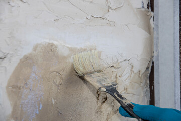 The builder applies soil to the wall. A painter paints the slope of a doorway with a brush, makes...