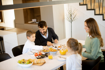 Young happy family talking while having breakfast at dining table