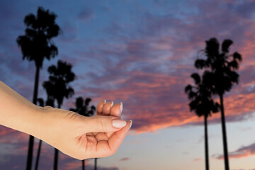 Hot summer sunset mock up. Travel and adventure themes. Woman hand on Malibu landscape background