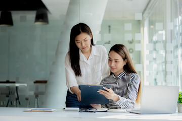 Two women looking at information on their laptops, two business women discussing brainstorming and implementation plans, form a partnership to form a startup. Management concept of startup company.