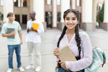 Loans for education concept. Portrait of happy indian female student posing outdoors in campus with...