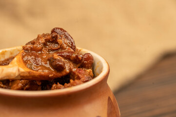 Stewed beans with meat in a small pot. A traditional rustic dish. Close-up, selective focus.