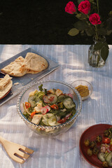 Summer time meal outside arranged on a white table cloth. Salads, breads, olives and drinks. Alfresco food concept image.