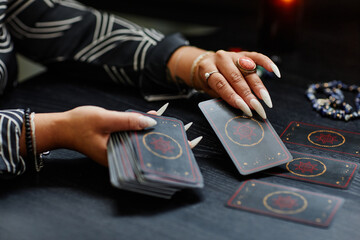 Closeup of unrecognizable African American woman reading tarot cards over table in fortune tellers shop, copy space