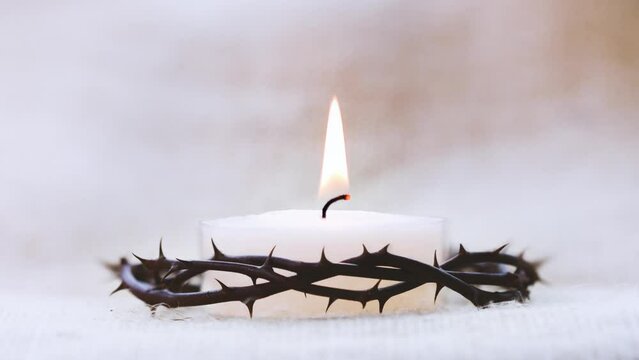 Crown of thorns symbolizing the suffering cross, death and resurrection of Jesus Christ and brightly shining candle background