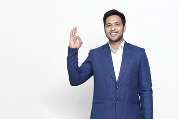 Portrait of a cheerful young man showing okay gesture isolated on the white isolated background.