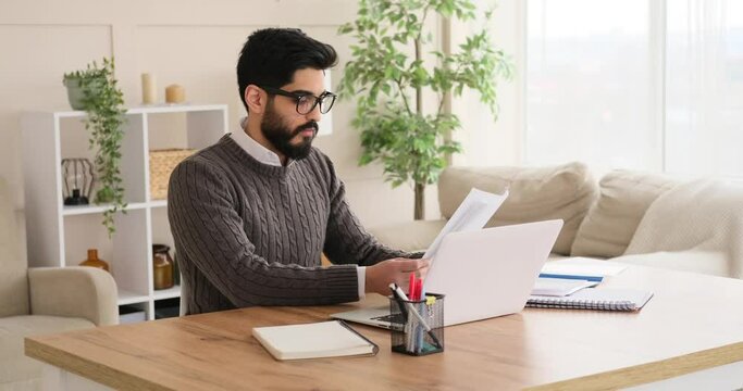Businessman using laptop and analyzing document at office