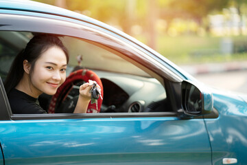 young happy asian woman hold a key in car with sunlight