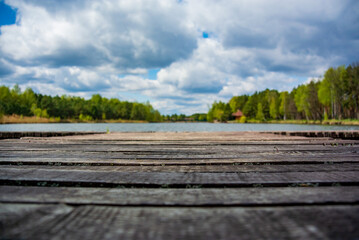 Blurred background with wooden pier on the shore of a large lake in the forest. Wonderful spring landscape. A cozy place for rest, meditation and fishing
