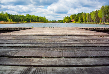 Blurred background with wooden pier on the shore of a large lake in the forest. Wonderful spring landscape. A cozy place for rest, meditation and fishing
