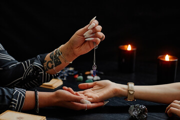Close up of gypsy holding magic crystal over palm of young woman and reading her destiny in fortune...