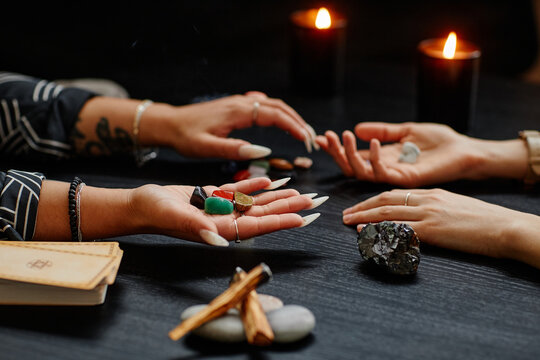 Close up of gypsy holding crystals and reading clients destiny in dark fortune telling shop