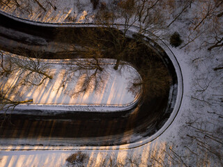 A road bending 180 degrees like a U turn with snow covered surrounding.