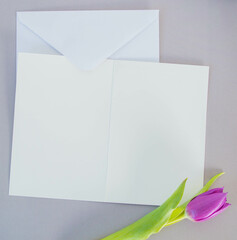 white card and envelope on grey ground with tulips with space for text