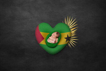 Newborn portrait on heart in color of national flag. Photography peace concept. Sao Tome