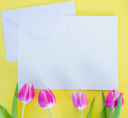 white card and envelope on yellow ground with pink tulips with space for text