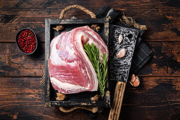 Organic uncooked Pork belly, raw bacon meat in a wooden plate with thyme. Wooden background. Top...