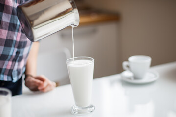 the girl is preparing morning coffee. the girl is preparing breakfast. the girl pours milk in a latte