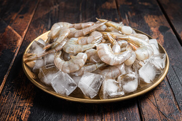 Fresh Raw tiger white shrimp prawn peeled with tail on ice. Wooden background. Top view