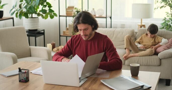 Father analyzing documents while mother and son using digital tablet in the background at home