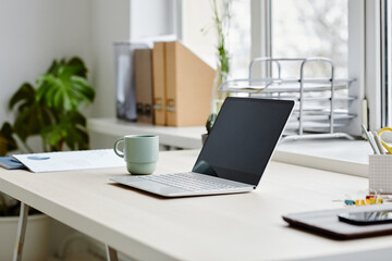 Minimal close up of opened laptop on desk in comfortable home office interior, copy space