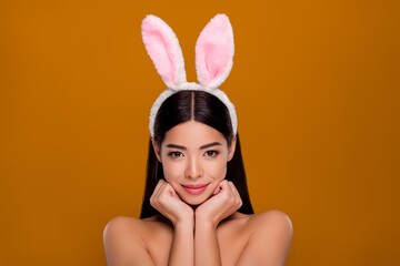 Obraz na płótnie Canvas Closeup photo of brunette asian girl wear easter hare ears mysterious flirty look camera arms close chest isolated pastel background