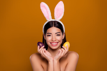 Closeup photo of asian ethnicity pretty girl wear easter fluffy ears hold painted eggs prepare...