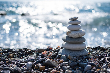 pyramid of stones balances on a pebble beach on a blurred background of the sea. concept meditation yoga zen