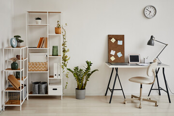 Minimal background image of cozy home office workplace in white tones decorated with green plants, copy space