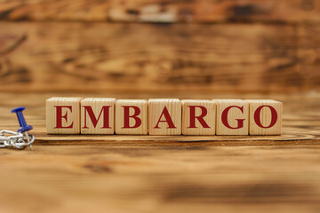 Fototapeta premium Embargo. Word on wooden blocks. Isolated on a gray background. Business. Politics. Economy. Conflict between Ukraine and Russia. Crisis, poverty, starvation. Conceptual.