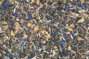 A mixture of green tea leaves and dried additives: cornflower petals, mango fruit, lemongrass, rose petals, and calendula petals - obrazy, fototapety, plakaty