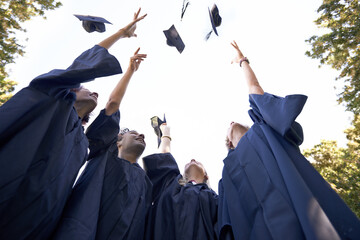 Our hard work has paid off. A group of college graduates celebrating by throwing their hats in the...