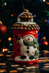 Christmas lantern with a snowman figurine against the background of multi-colored Christmas tree lights. Christmas decorations. bokeh. Christmas and New Year