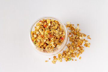 glass with dry cereals and pieces of dried fruits on a white background