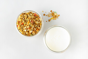 glass with dry cereal and glass with yogurt on white background