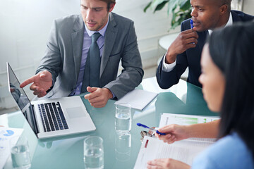 Presenting his results to the team. Shot of a businessman showing his colleagues something on a laptop during a meeting.