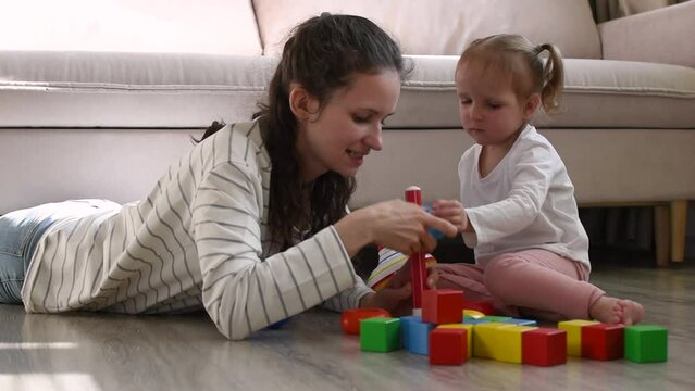 Mother and little girl is playing with toys.