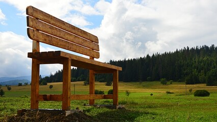 Huge monumental wooden bench as symbol of relax, placed in beautiful upland landscape on borderline...
